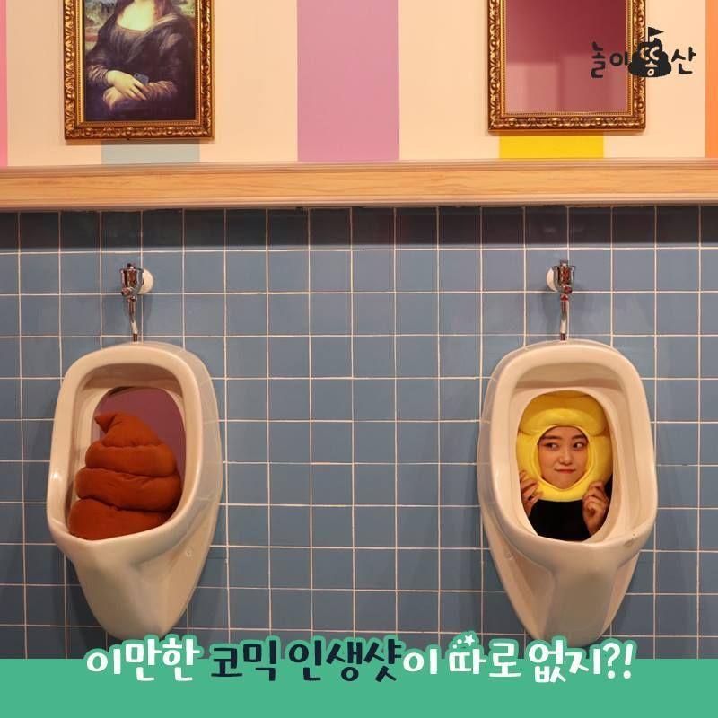 韓國大便主題展覽中，兩位遊客正在觀賞與報紙相關的雕塑，背景是花磚牆。